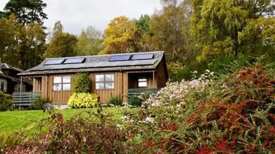 a small house with solar panels on top of it at Morenish Mews Killin Cottage in Morenish