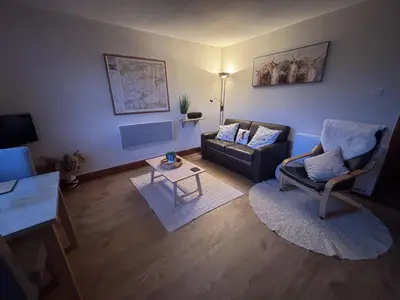 a living room with a couch and a chair at Morenish Mews Kenmore Cottage in Morenish