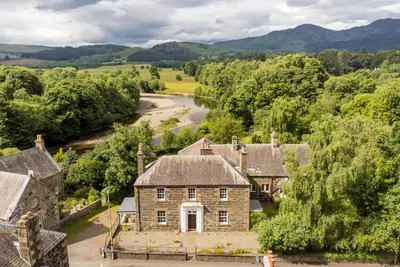 an aerial view of an old stone house with a river at Ruchearn in Comrie