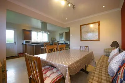 a dining room with a table and a kitchen at Tomanour in Comrie