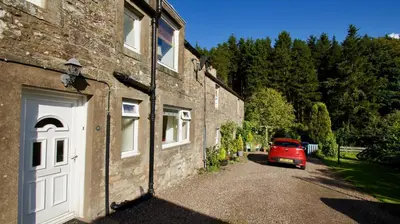 a red car parked next to a brick building at Waterside in Braco