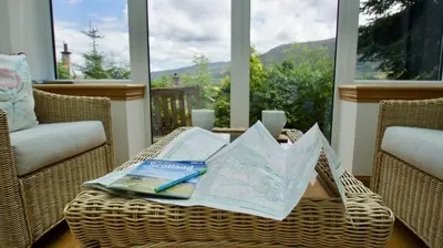 a wicker table with a map and a pen on it at View Cottage in Lochearnhead
