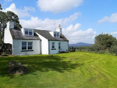 a white house on a grassy field at Airie Farmhouse in Castle Douglas