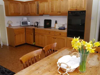 a kitchen with a wooden table with a vase of flowers at Airie Farmhouse in Castle Douglas
