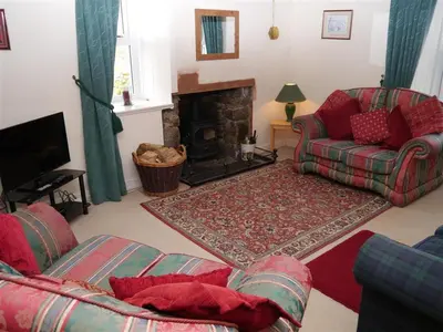 a living room with a couch and a fireplace at Airie Farmhouse in Castle Douglas