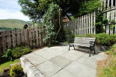 a bench sitting on a sidewalk next to a fence at Osprey View in Lochearnhead