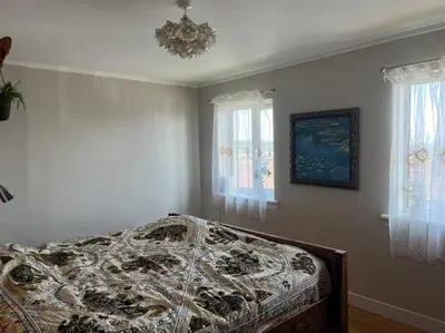 a bedroom with a bed and a chandelier and windows at Bright, comfy and peaceful house in Inverkeithing