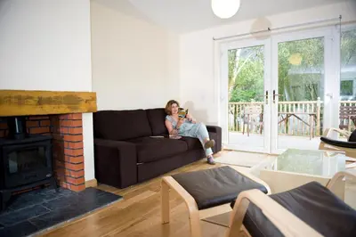 a woman sitting on a couch in a living room at Lochleven Seafood Cottage in Onich