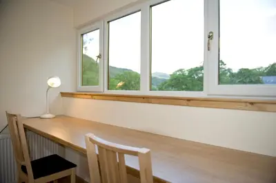 a room with a wooden desk with two windows at Lochleven Seafood Cottage in Onich