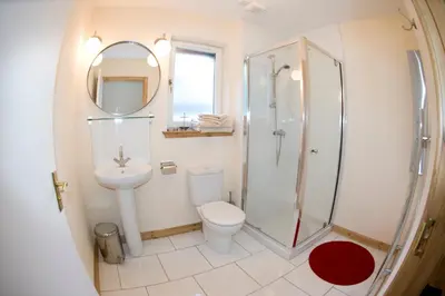 a bathroom with a shower and a toilet and a sink at Lochleven Seafood Cottage in Onich