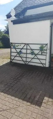 a white building with a gate with flowers on it at 2 Bed Cottage Sleeps 2 - Parking Pet Friendly in Dunoon