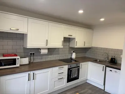 a kitchen with white cabinets and white appliances at 16 Macgregor court, Oban in Oban