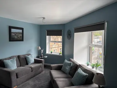 a living room with a couch and two windows at 16 Macgregor court, Oban in Oban