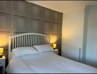 a bedroom with a large white bed with two lamps at Camisila in Campbeltown