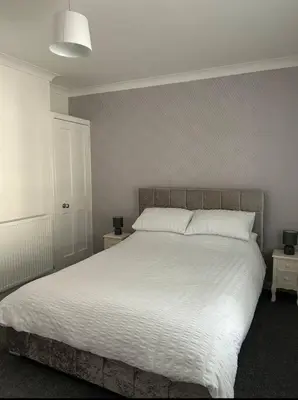 a bedroom with a large bed with white sheets at Camisila in Campbeltown