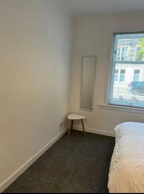 a bedroom with a bed and a table and a window at Camisila in Campbeltown