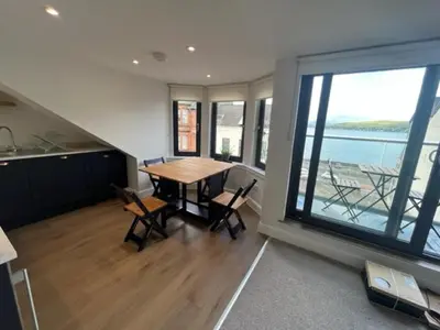 a dining room with a table and a large window at Waverley Apartments, Crow's Nest in Gourock