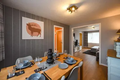 a dining room with a table with chairs and a room with a living room at Links Golf Villa in Troon