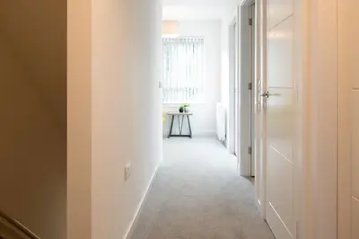 a hallway with a white door and a table at Beautiful Glasgow South Home - Pass the Keys in Glasgow