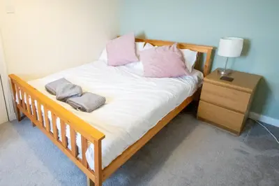 a bedroom with a bed with white sheets and pink pillows at Tranquil 2Bed/2Bath Duplex Falkirk in Falkirk