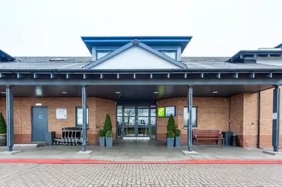 a brick building with two benches in front of it at Holiday Inn Express Edinburgh Airport by IHG in Ingliston