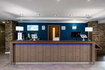 a bar in a hotel lobby with a blue wall at Holiday Inn Express Edinburgh Airport by IHG in Ingliston