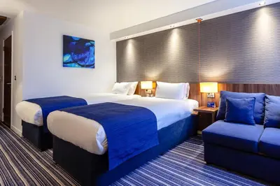 a hotel room with two beds and a couch at Holiday Inn Express Edinburgh Airport by IHG in Ingliston