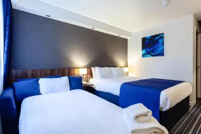 two beds in a hotel room with blue and white at Holiday Inn Express Edinburgh Airport by IHG in Ingliston