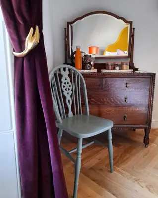 a chair next to a dresser and a mirror at Ben A'an House in Callander