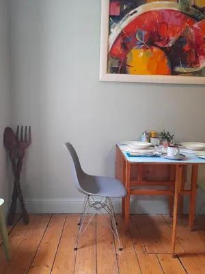 a chair next to a desk with a painting on the wall at Ben A'an House in Callander