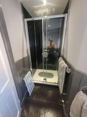 a man taking a picture of a shower in a bathroom at 2 Kilkerran Road in Campbeltown