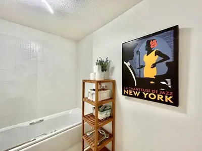 a bathroom with a poster on the wall next to a bathtub at Spekman's 3 Bedroom Ap - 20min Glasgow & Edinburgh in Falkirk