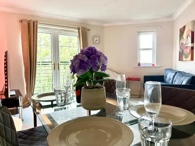 a living room with a glass table and purple flowers at Spekman's 3 Bedroom Ap - 20min Glasgow & Edinburgh in Falkirk
