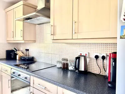 a kitchen with white cabinets and a black counter top at Spekman's 3 Bedroom Ap - 20min Glasgow & Edinburgh in Falkirk
