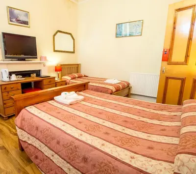 a hotel room with two beds and a television at Corstorphine Lodge Hotel in Edinburgh