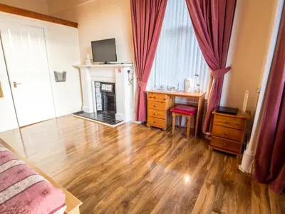a bedroom with a wooden floor with a fireplace and red curtains at Corstorphine Lodge Hotel in Edinburgh