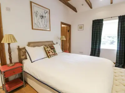 a bedroom with a large white bed and a window at Kilnmark Bothy in Thornhill