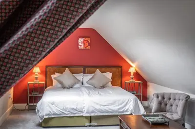 a bedroom with a bed and a red wall at Prince's Cottage in Thornhill