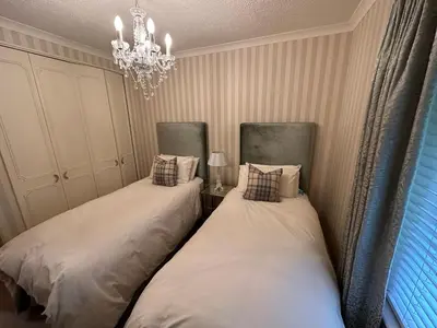 two beds in a room with a chandelier at One Dunbar Court Gleneagles Village in Auchterarder
