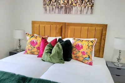 a white bed with colorful pillows on top of it at Three Bedrooms House By Sensational Stay Short Lets & Serviced Accommodation With Free Parking & Wi-fi in Ballingry