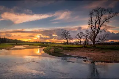 a sunset over a river with trees and clouds at Luxury Guest House Getaway for 2 in Drymen