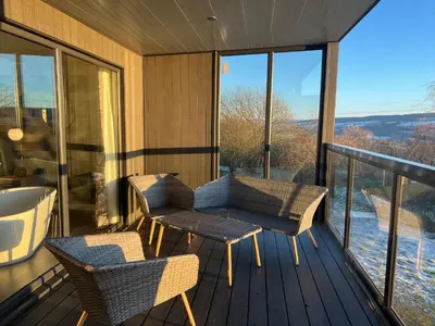 a balcony with chairs and a tub on a deck at Loudoun Mains Luxury Lodges in Newmilns