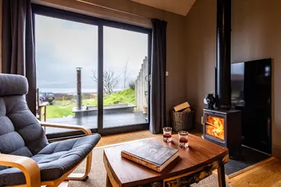 a living room with a fireplace and a couch and a table at Jura - The Black Hut in Isle of Jura