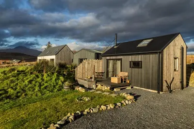 a small house with a black roof on a hill at Jura - The Black Hut in Isle of Jura