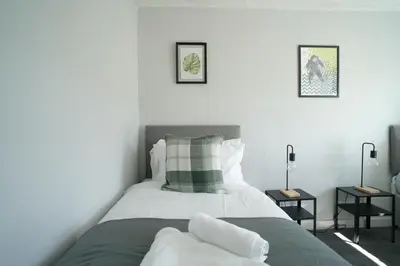 a bedroom with two beds and two side tables at McCracken House in Uddingston