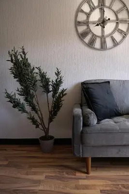 a living room with a couch and a clock on the wall at Sauchie House in Sauchie