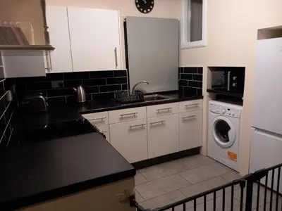 a kitchen with white cabinets and a washing machine at The WEE HOUSE Balvicar Isle of Seil in Balvicar