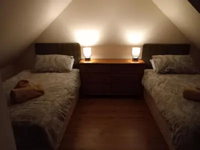two beds in a attic room with two lights on them at The WEE HOUSE Balvicar Isle of Seil in Balvicar