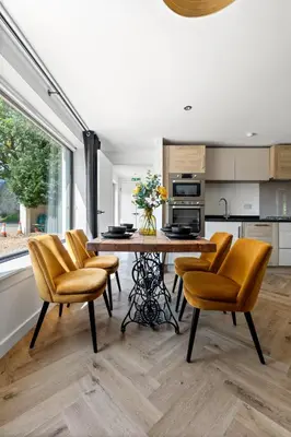 a kitchen with a wooden table and chairs and a table and a kitchen at Peterswell Holiday Cottage in Houston
