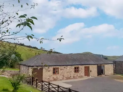 an old stone barn with a fence in front of it at South Steading in West Kilbride